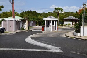 Un lotissement résidentiel fermé, doté d’un petit kiosque, d’un espace extérieur couvert avec des sièges et d’une rue où la chaussée est légèrement incurvée.
