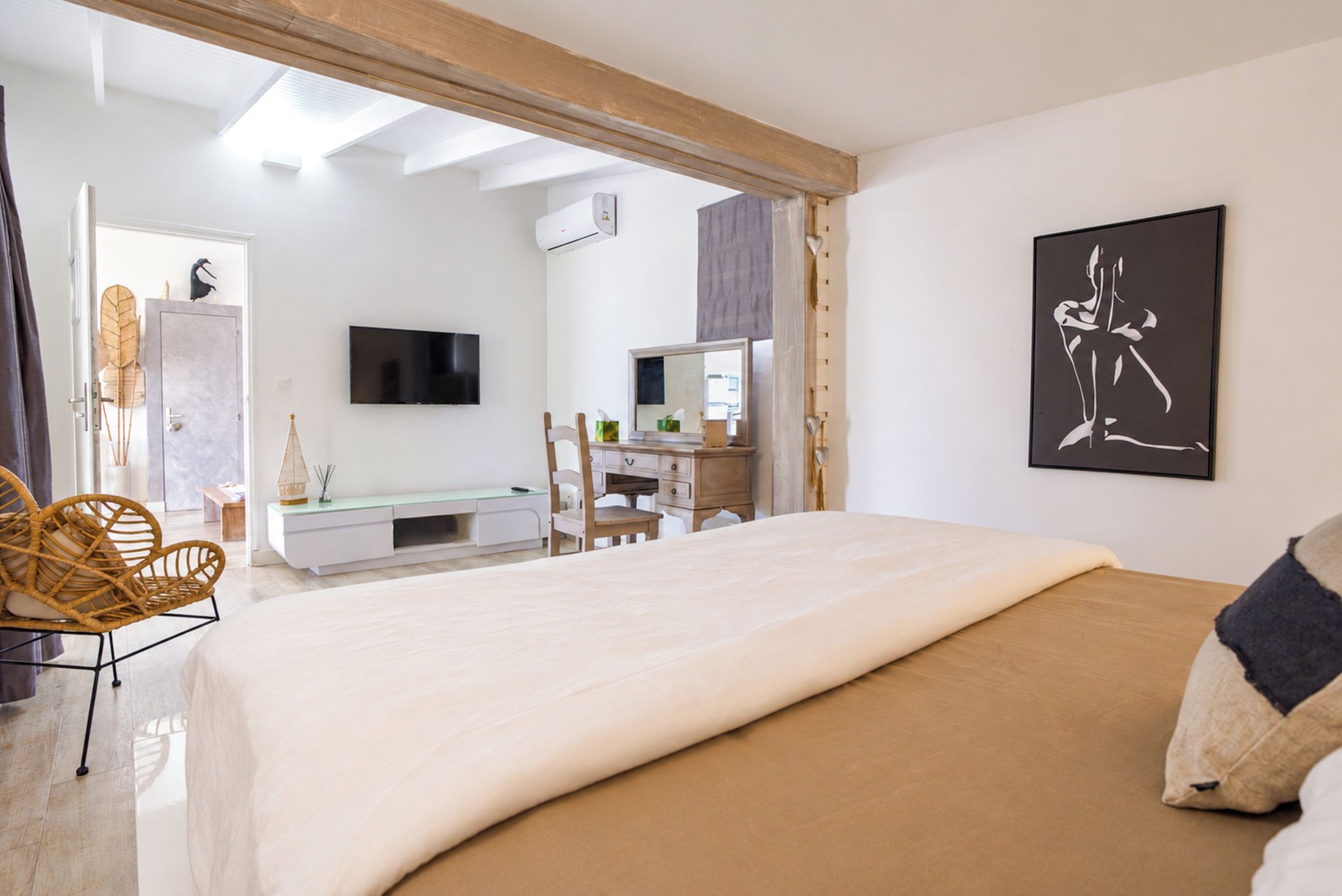 Un dormitorio con cama, cómoda, televisión y un cuadro.