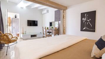 Un dormitorio con cama, cómoda, televisión y un cuadro.
