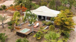 Una casa con un porche cubierto, mobiliario exterior y un jacuzzi.