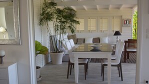 A dining area with a glass table, white chairs, and a potted plant. - Guest-House In A Palmgrove For A Couple. Space, Privacy And Silence (Saint Martin)