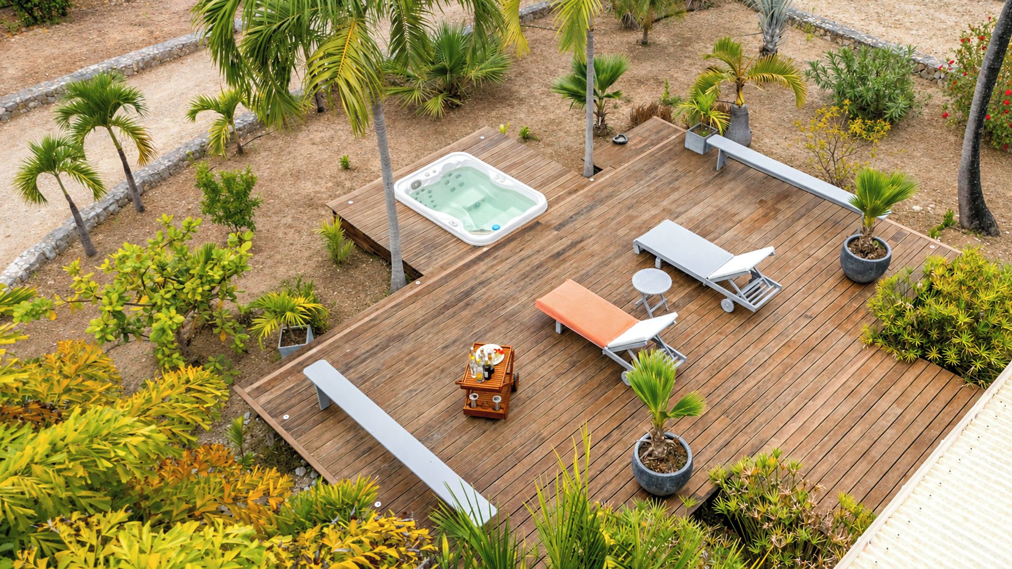 Um deck de madeira com banheira de hidromassagem, espreguiçadeiras e plantas em vasos.