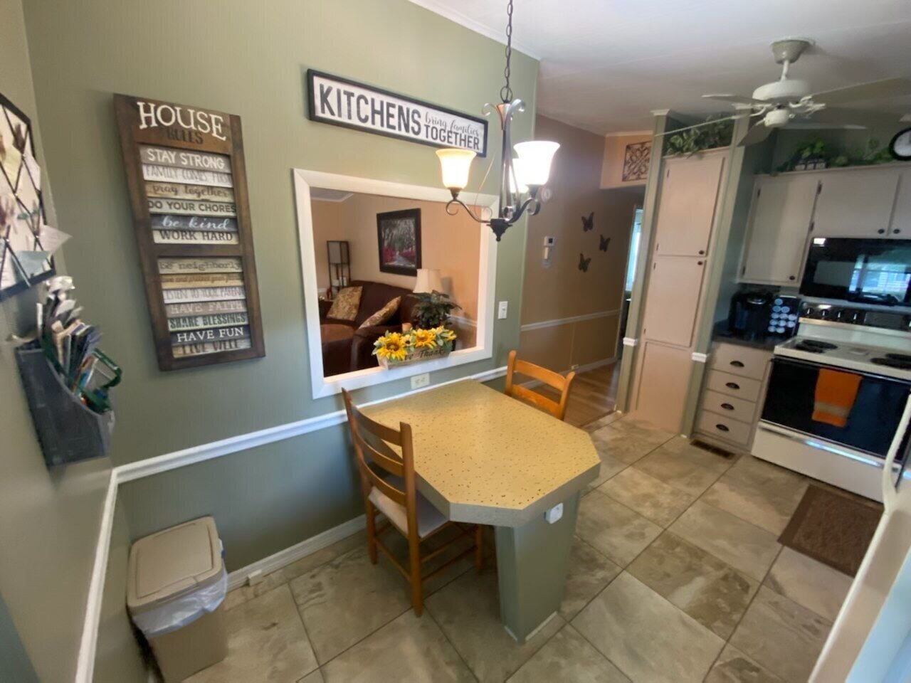 Una cucina compatta con zona pranzo, una ventola a soffitto e vista sul soggiorno.