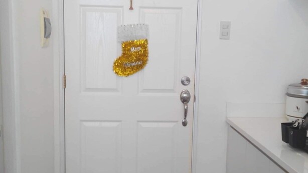 A white door with a silver cross, a gold and silver Christmas stocking, and a silver doorknob. - Affordable Condo with FREE WIFI and Amenities (Cebu City)