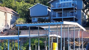 Propiedad frente al agua con muelle techado, piscina y una casa de varios pisos.