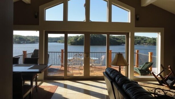 Una habitación amplia con un gran ventanal corredero que da a un balcón con vistas a un lago.