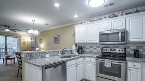 Una cocina con armarios blancos, microondas integrado, horno doble y lavavajillas.