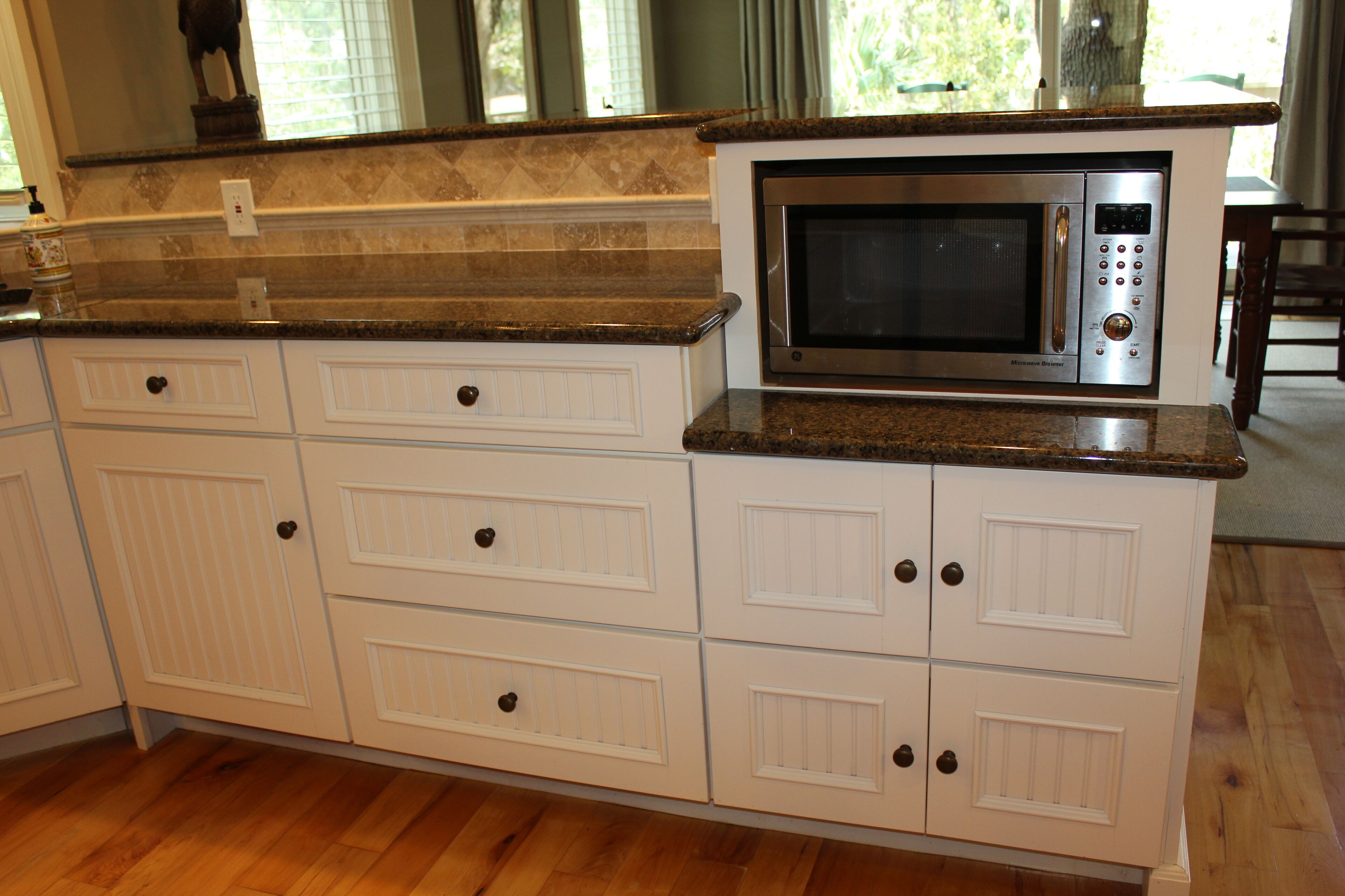 A kitchen with white cabinetry, a granite countertop, and a built-in microwave oven.