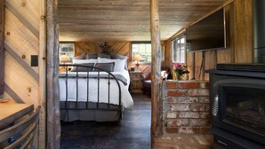 Une chambre à coucher de style rustique, avec un lit, une cheminée en briques et un téléviseur.