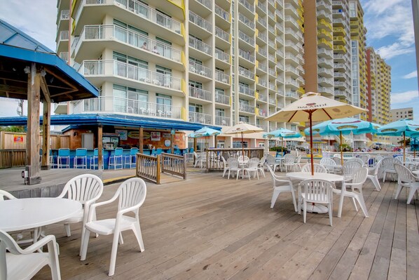 A beachfront hotel with outdoor seating, a pool, and multiple balconies.