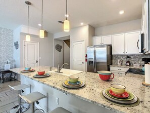 A modern kitchen with a central island, stainless steel appliances, and pendant lighting.