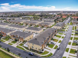 A residential area with multiple-story houses, a main road, and a clear sky.