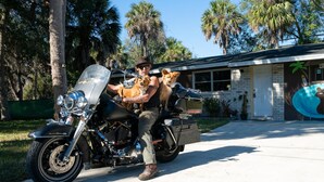 A man on a motorcycle with two dogs, parked in front of a house with a mural. - Hippohead Casita Pets stay free bring your Humans! (Homosassa)
