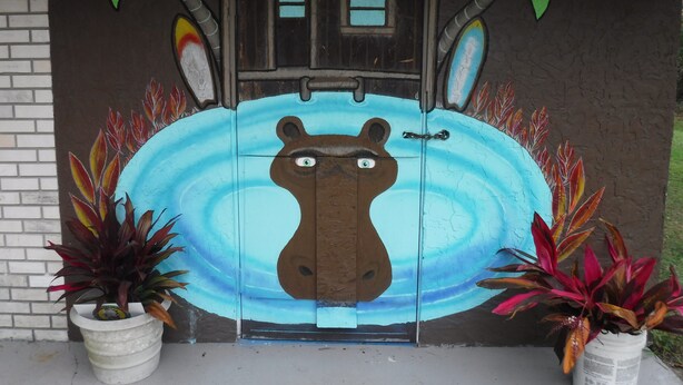 A door with a mural of a hippopotamus, two palm trees, and a sign for Hippo Head Hotel. - Hippohead Casita Pets stay free bring your Humans! (Homosassa)