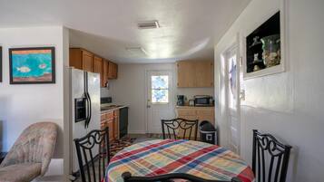A compact kitchen with wooden cabinets, a refrigerator, a microwave, and a coffee maker.