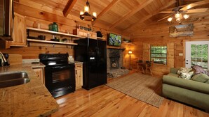 Interior de una cabaña de madera con cocina, comedor y chimenea.