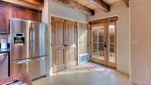 A kitchen with wooden cabinets, a stainless steel refrigerator, and a wooden door leading to a patio.