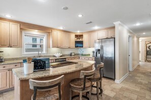 A modern kitchen with wooden cabinets, a stainless steel refrigerator, and a granite countertop. - 10% OFF BEACH FRONT COTTAGE! C 30A BIKE/SHOP/RESTAURANTS (Panama City Beach)