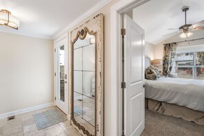 A bedroom with a bed, a ceiling fan, and a large mirror with a decorative frame. - 10% OFF BEACH FRONT COTTAGE! C 30A BIKE/SHOP/RESTAURANTS (Panama City Beach)