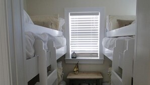Un dormitorio con literas, una mesita pequeña y una ventana con persianas.