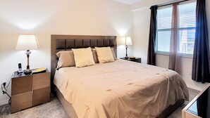 A bedroom with a bed, two bedside tables, a ceiling fan, and a window with curtains. - Family Fun: Condo near Theme Parks & Pools! (Kissimmee)
