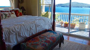A bedroom with a large bed, a bench, and a view of the sea through a sliding glass door. - Ocean View Villa & Cottage located 5 min Drivefrom Megans Bay with Cocktail Pool (St Thomas)