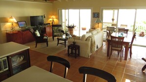 A spacious living area with a television, comfortable seating, a dining table, and a ceiling fan. - Ocean View Villa & Cottage located 5 min Drivefrom Megans Bay with Cocktail Pool (St Thomas)
