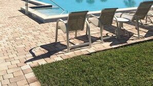 A swimming pool with lounge chairs and palm trees.