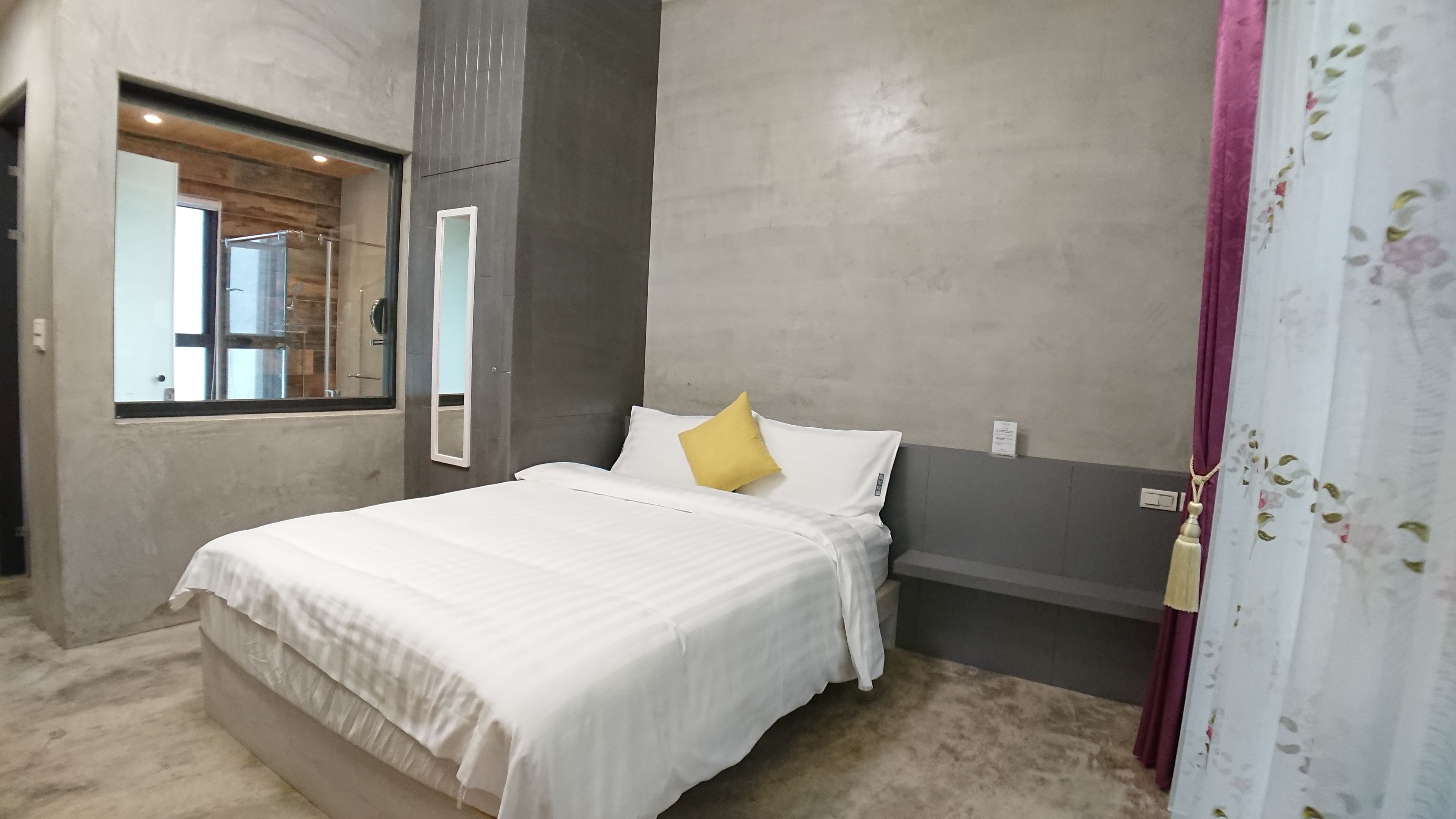 A modern bedroom with a large bed, a window, and a mirror.