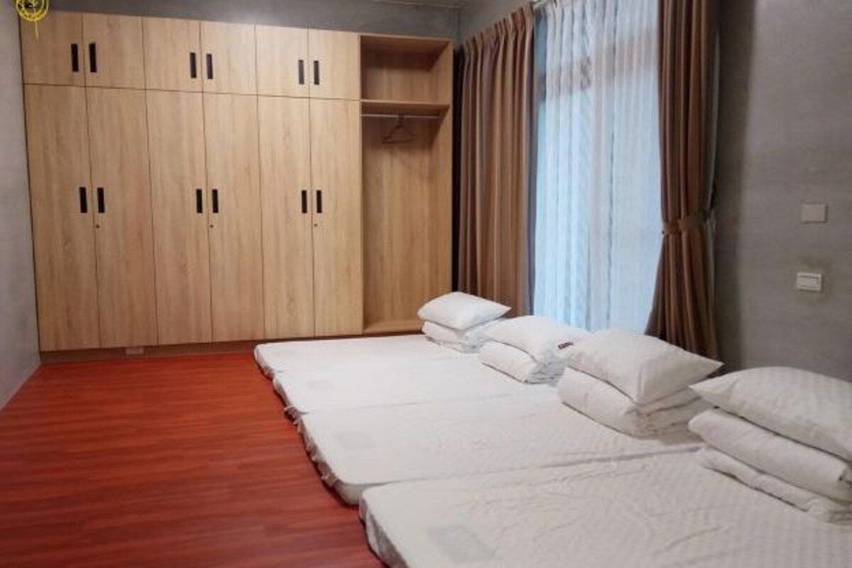 A room with a wooden wardrobe, a bed with white bedding, and a window with curtains.