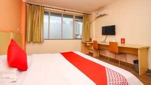 A hotel room with a bed, a desk, two chairs, a TV, and a window with curtains. - YuanMan Hotel (Huizhou)