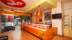 A reception desk with a red and white sign, a clock, and a television on the wall. - YuanMan Hotel (Huizhou)