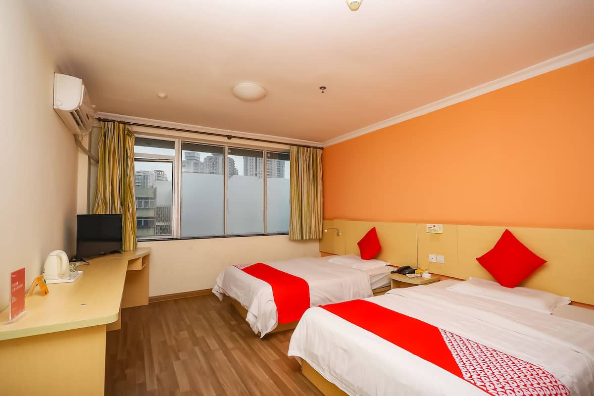 A hotel room with two beds, a desk with a computer, and a window with curtains.