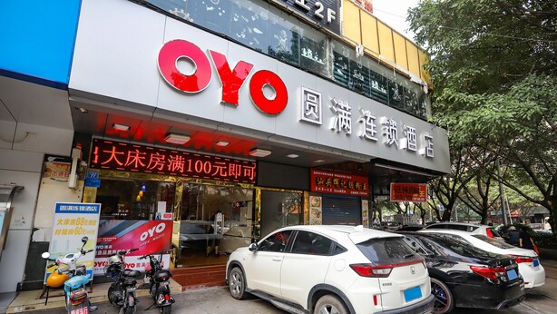 A hotel with a prominent 'OYO' sign, multiple parked cars, and a few scooters outside. - YuanMan Hotel (Huizhou)