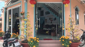 A building entrance with a staircase leading inside, potted plants, and a motorcycle parked outside.
