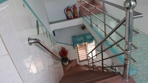 A staircase with metal railings and a handrail, leading to an upper level with a window and a potted plant.