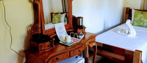 Habitación de hotel con cómoda de madera, espejo, refrigerador pequeño, cama con cubrecama blanco y televisor montado en la pared.