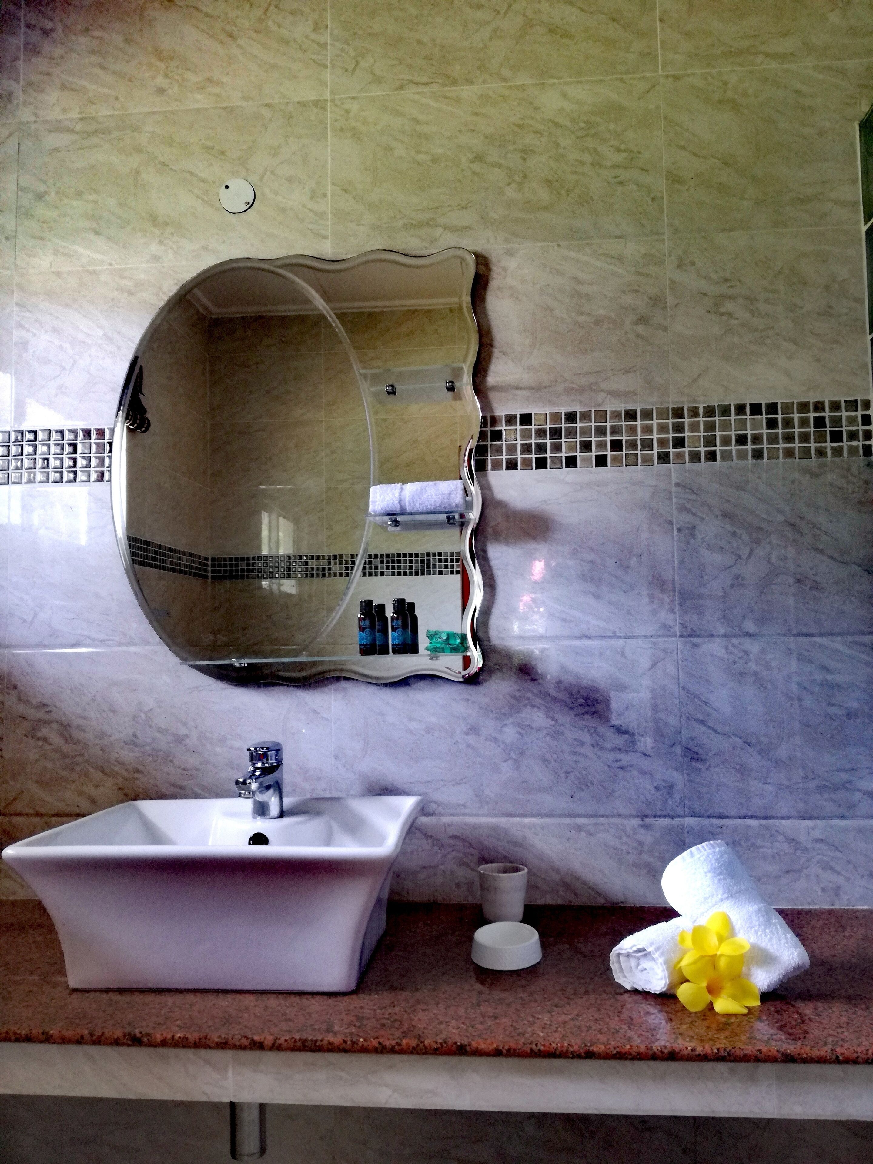 A bathroom with a white sink, a mirror, and toiletries.