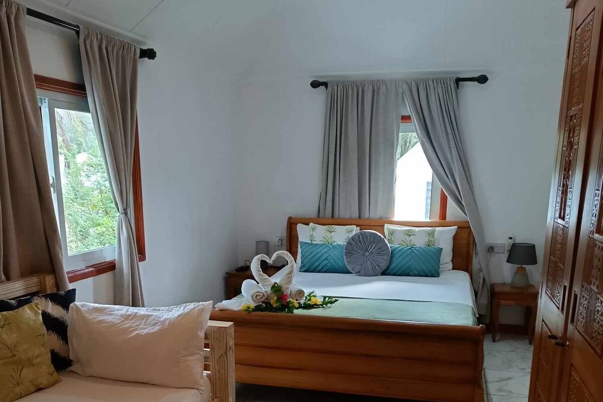 A hotel room with a wooden bed, a sofa, and a cabinet.