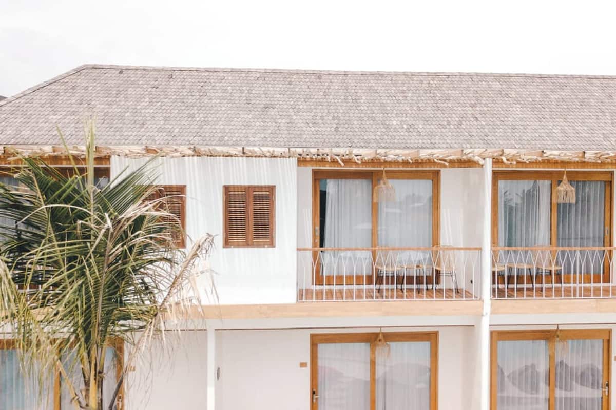 A two-story building with wooden balconies, large windows with shutters, and a thatched roof.