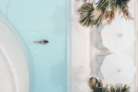 Una piscina al aire libre, sombrillas, sillones reclinables de piscina. Canggu Village