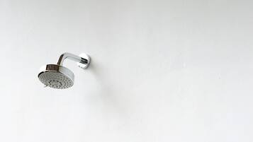 A bathroom with a shower, a faucet, and three bottles of liquid.