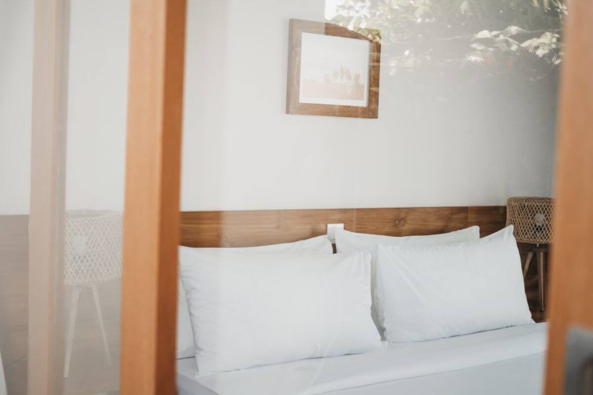 A neatly made bed with white linens, a wooden headboard, and a framed picture on the wall.