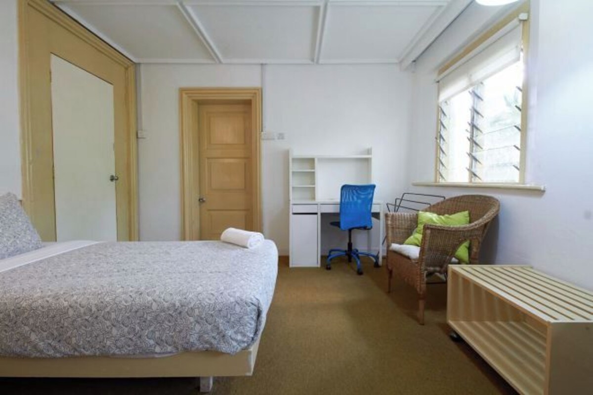 Een slaapkamer met een bed, een bureau, een stoel en een radiator.