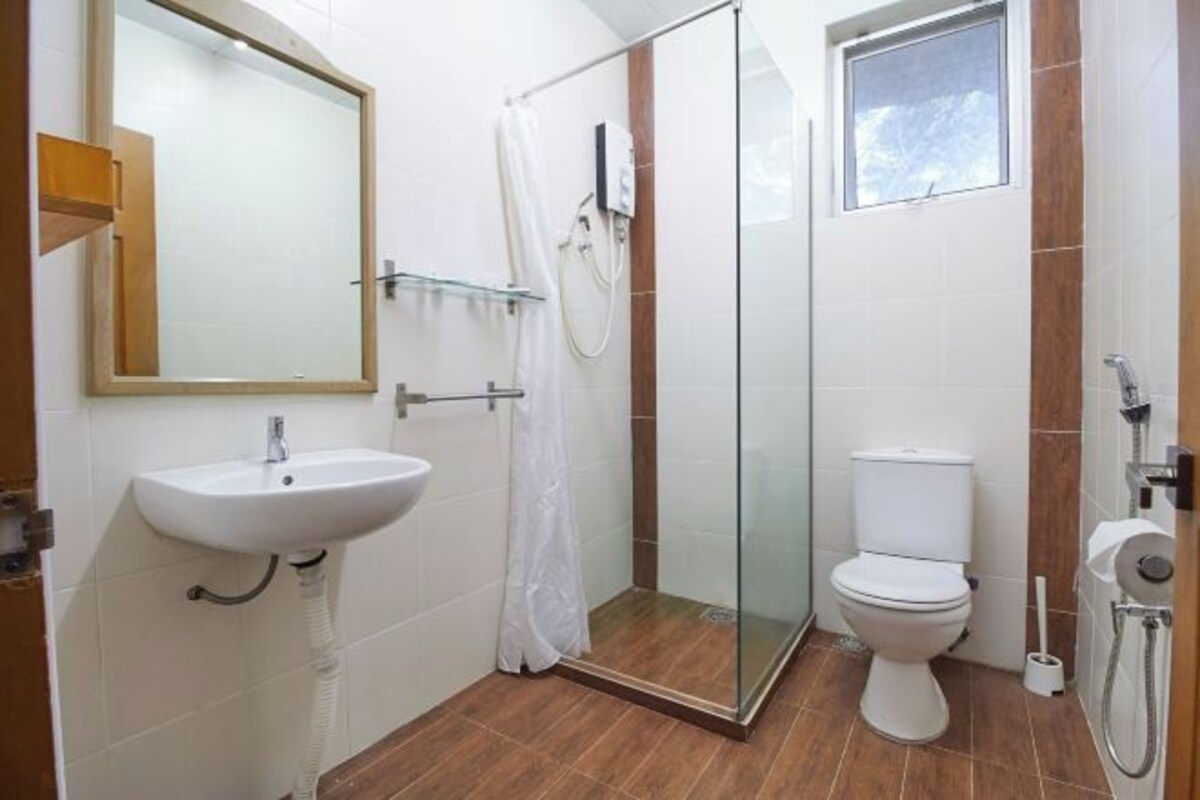 Een badkamer met een witte wastafel, een douchecabine van glas en een toilet.