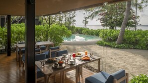 Area pranzo all'aperto con vista su piscina e oceano.