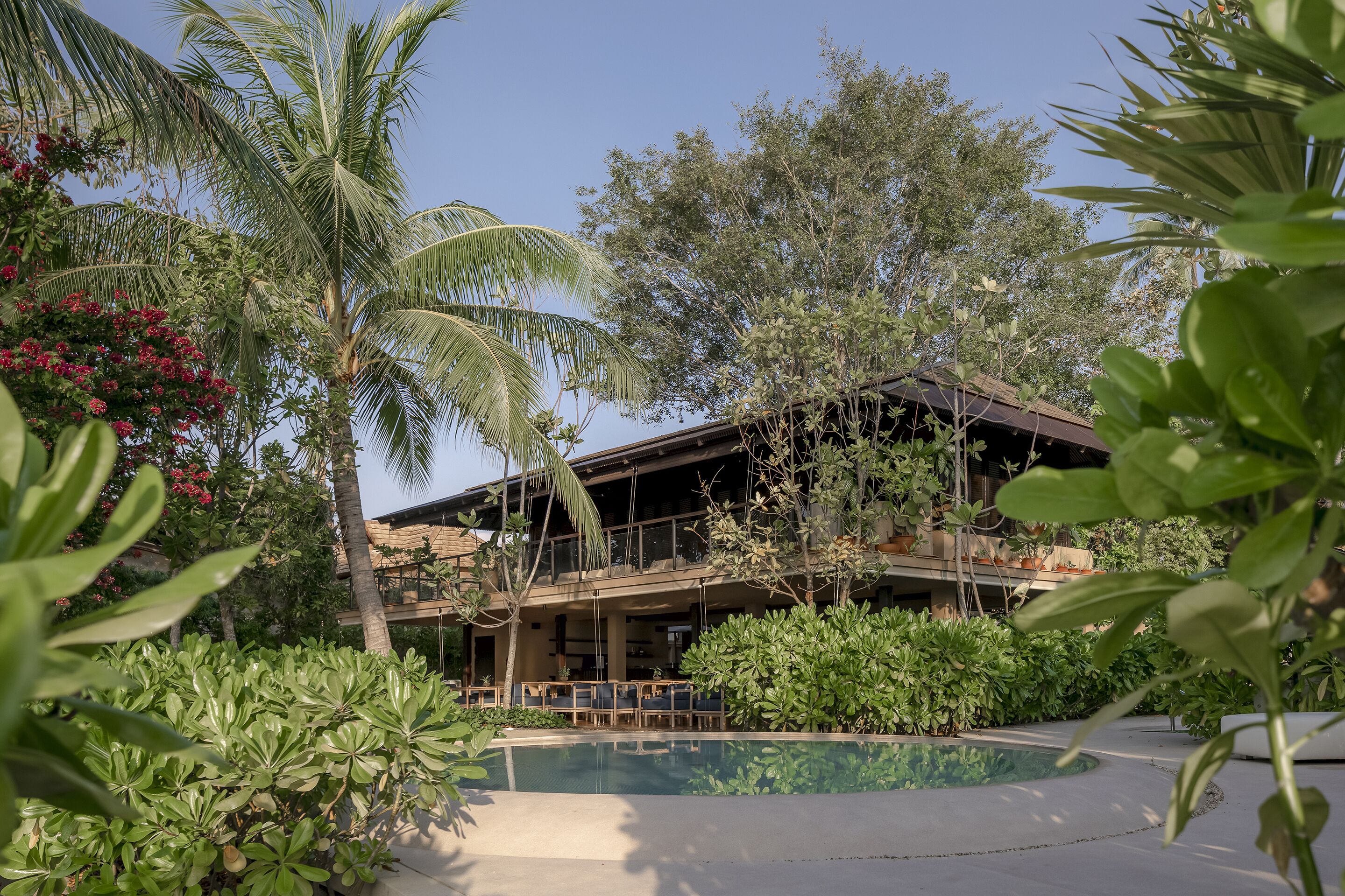 A resort with a pool, palm trees, and lush greenery.