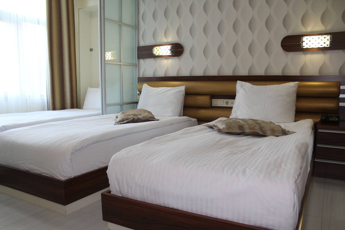 A hotel room with two beds, a wooden headboard, and a patterned wall.
