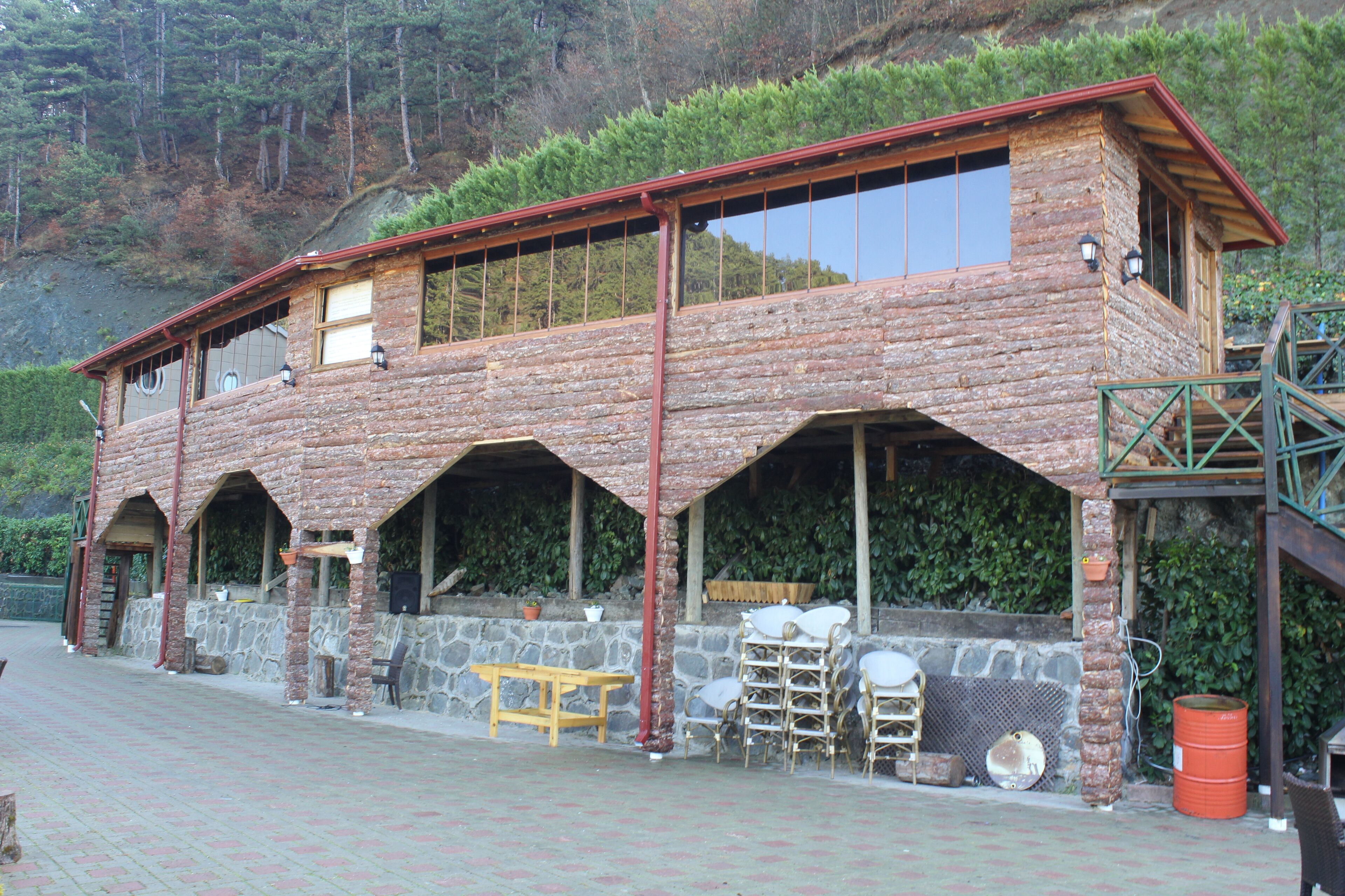 Uma cabana rústica de toras com base de pedra, várias janelas e área de estar externa.