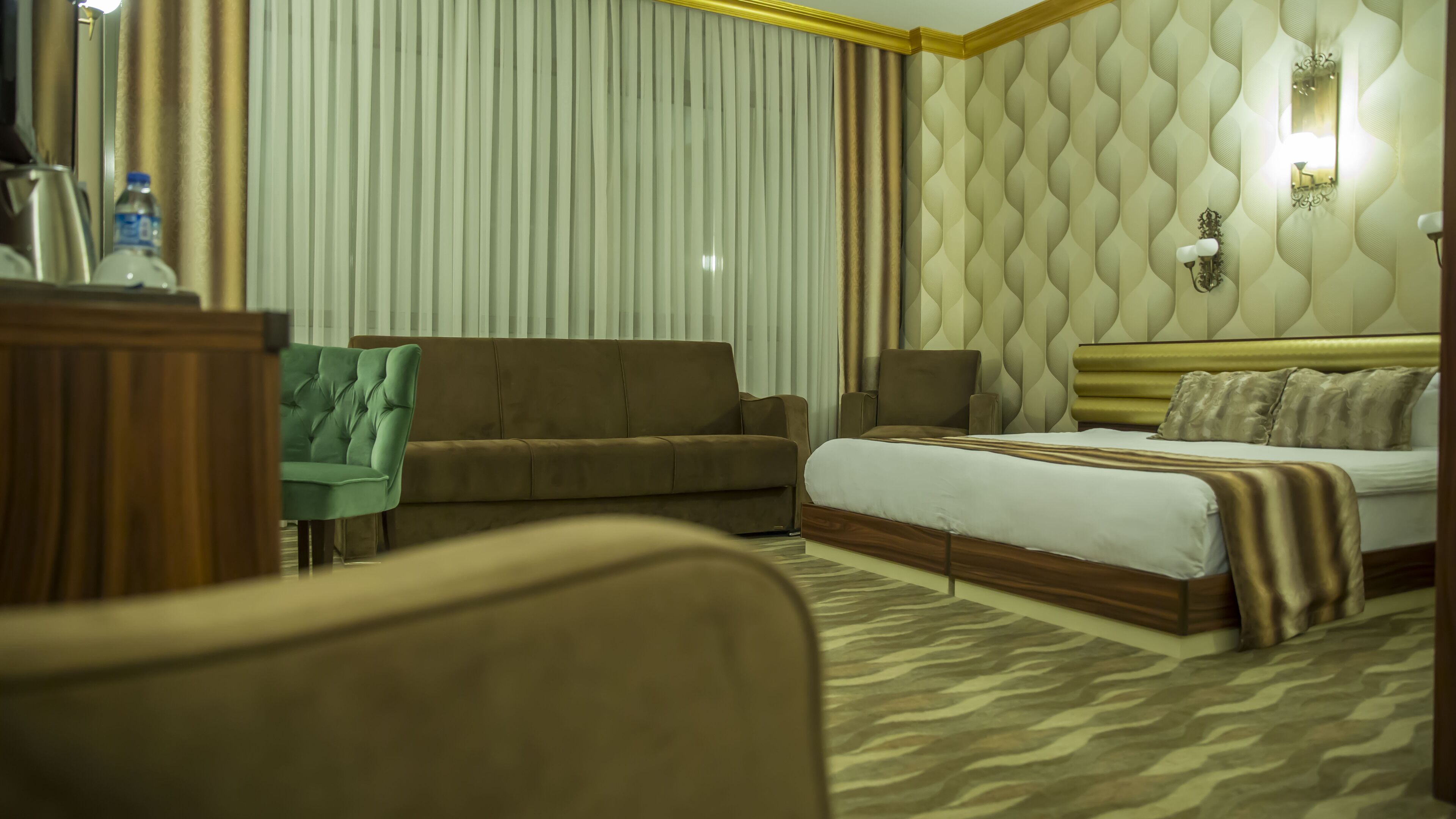 A hotel room with a bed, a sofa, a chair, and a desk.